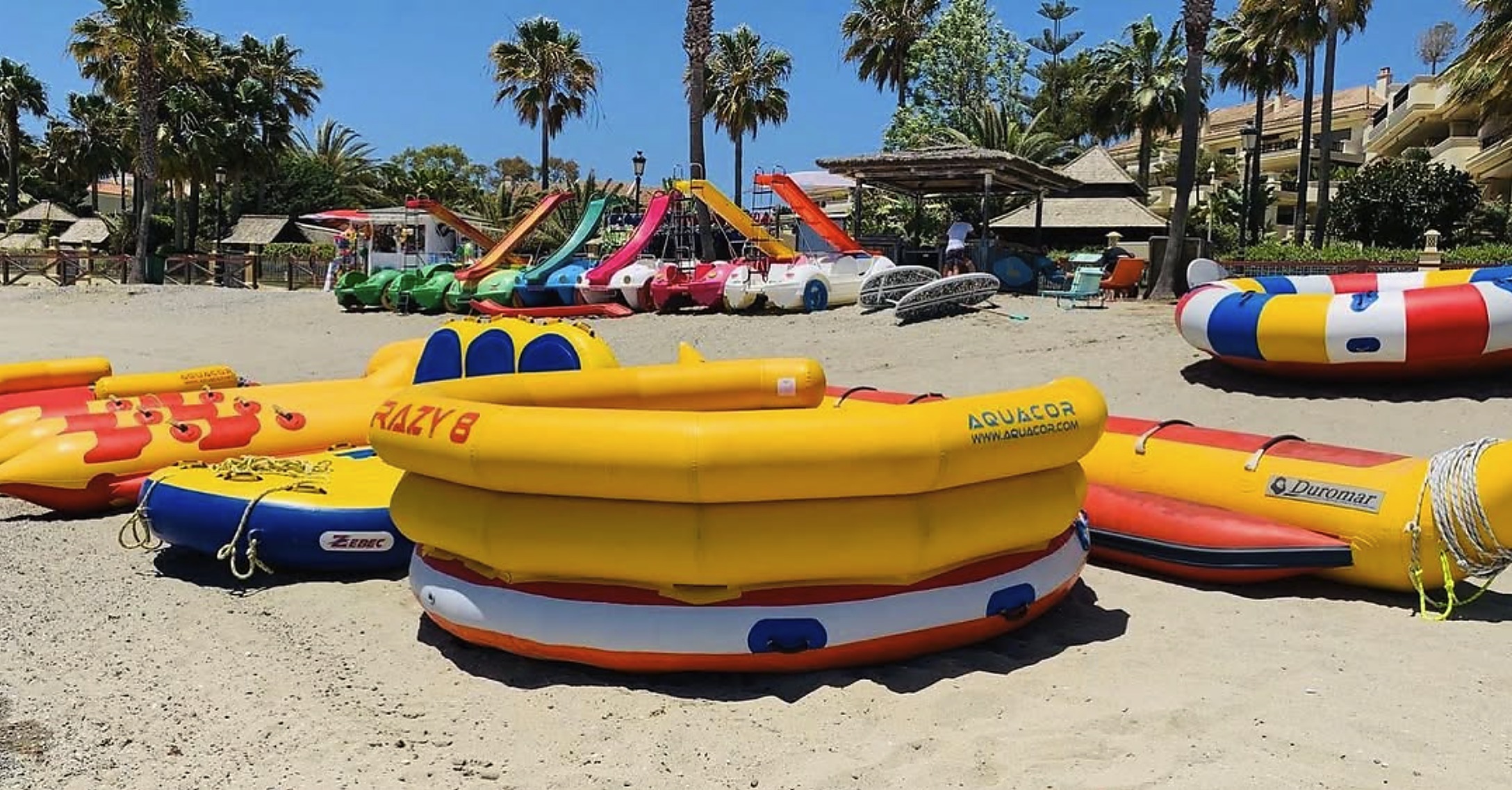 Colorful pedal boats with slides lined up on the Marbella beach