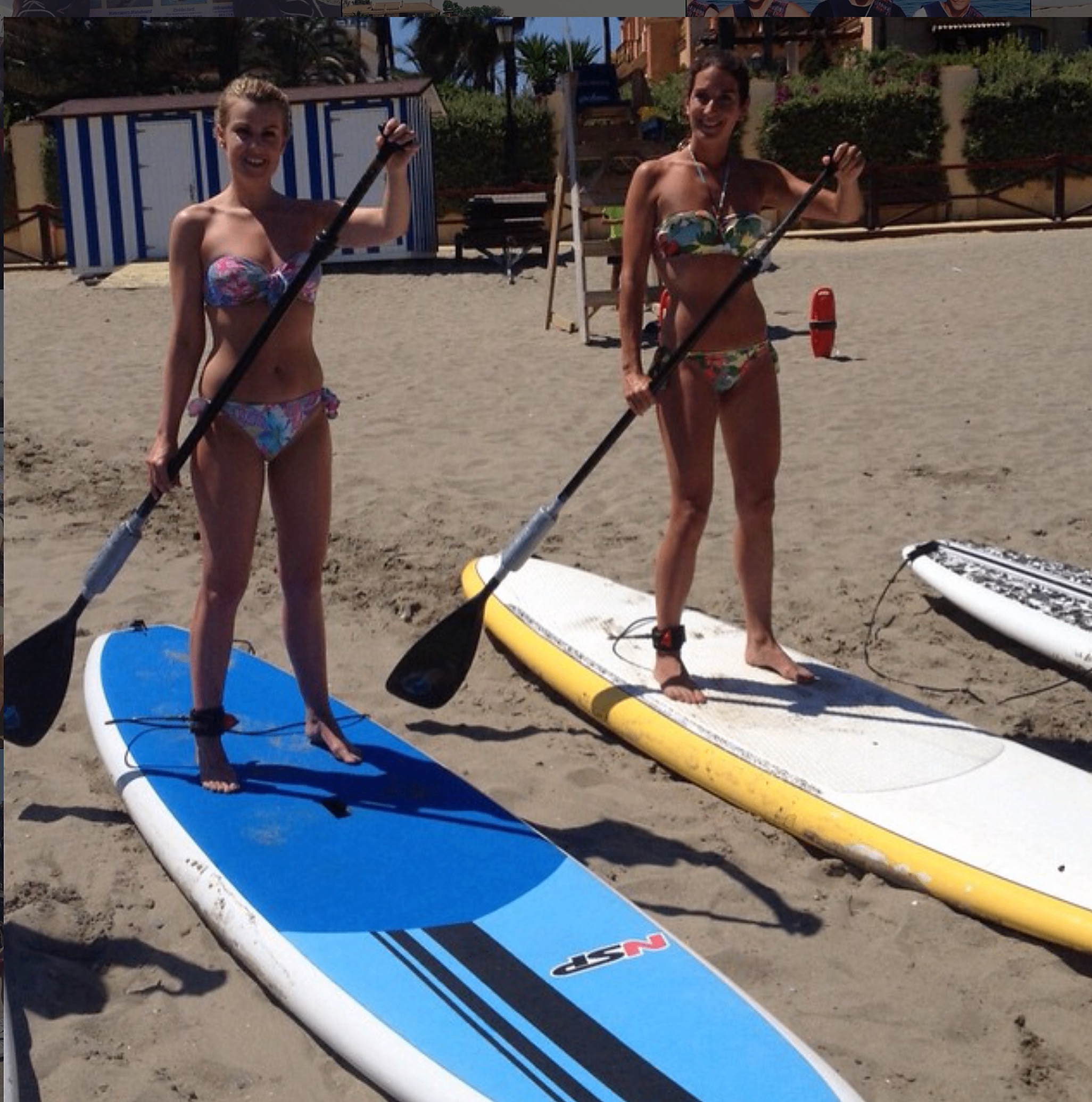 Two women standing with paddle boards on the Marbella beach