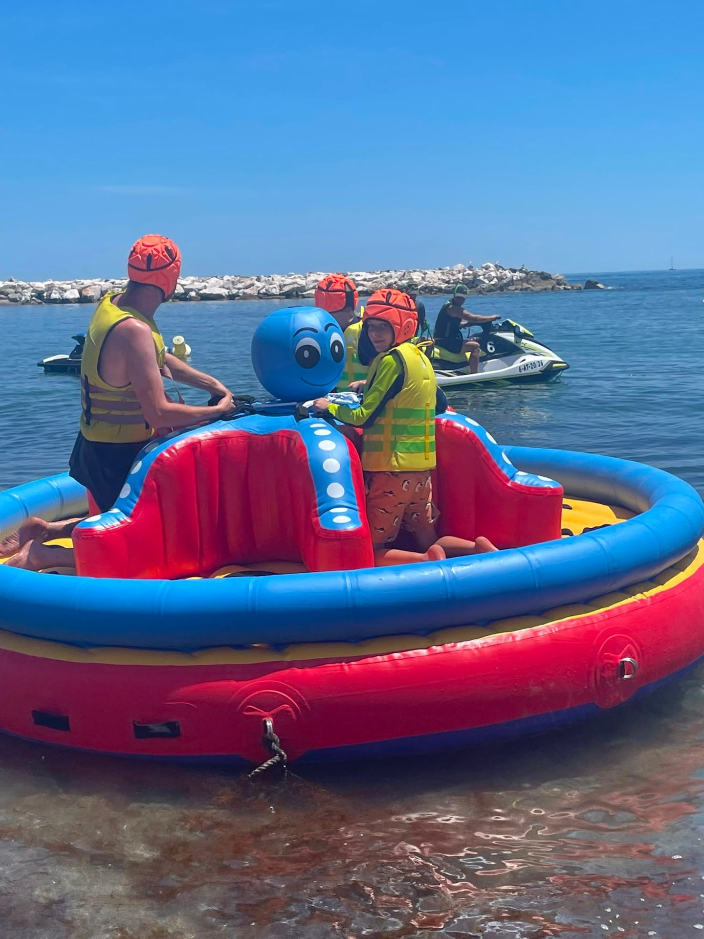 Riders in helmets and life vests on the octopus inflatable at Puerto Banús