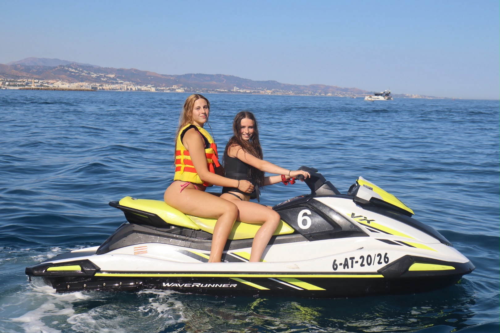 Two friends on a yellow Yamaha WaveRunner jet ski off Puerto Banús