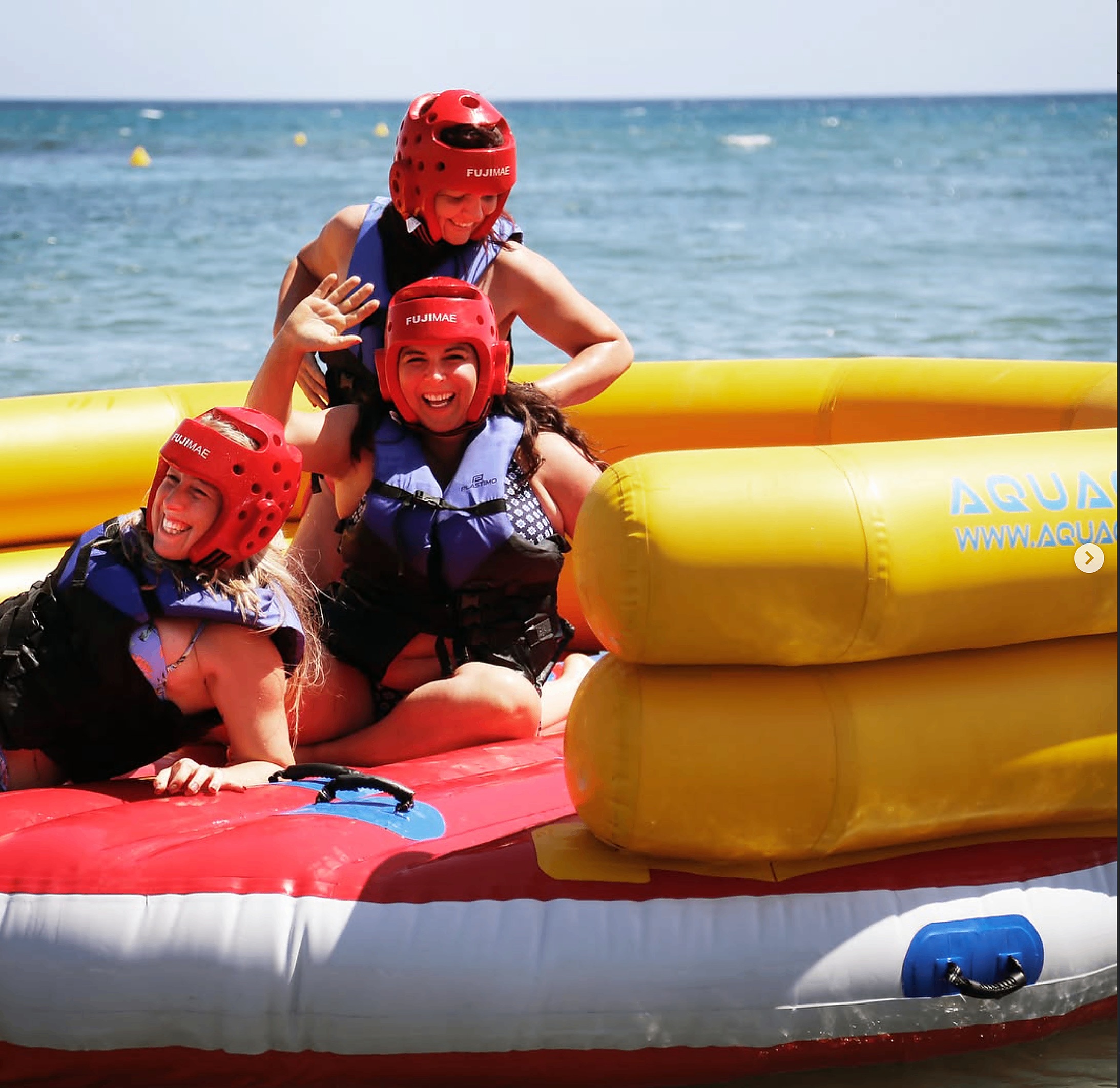 Friends in red helmets laughing on the Hollywood Watersports sofa